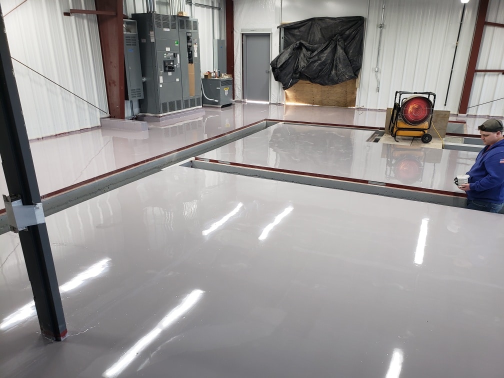 A photo showing a commercial floor with a glossy and seamless finish, created by the application of a resinous epoxy coating. The coating enhances the durability, slip resistance, and overall appearance of the floor, making it suitable for high-traffic areas.