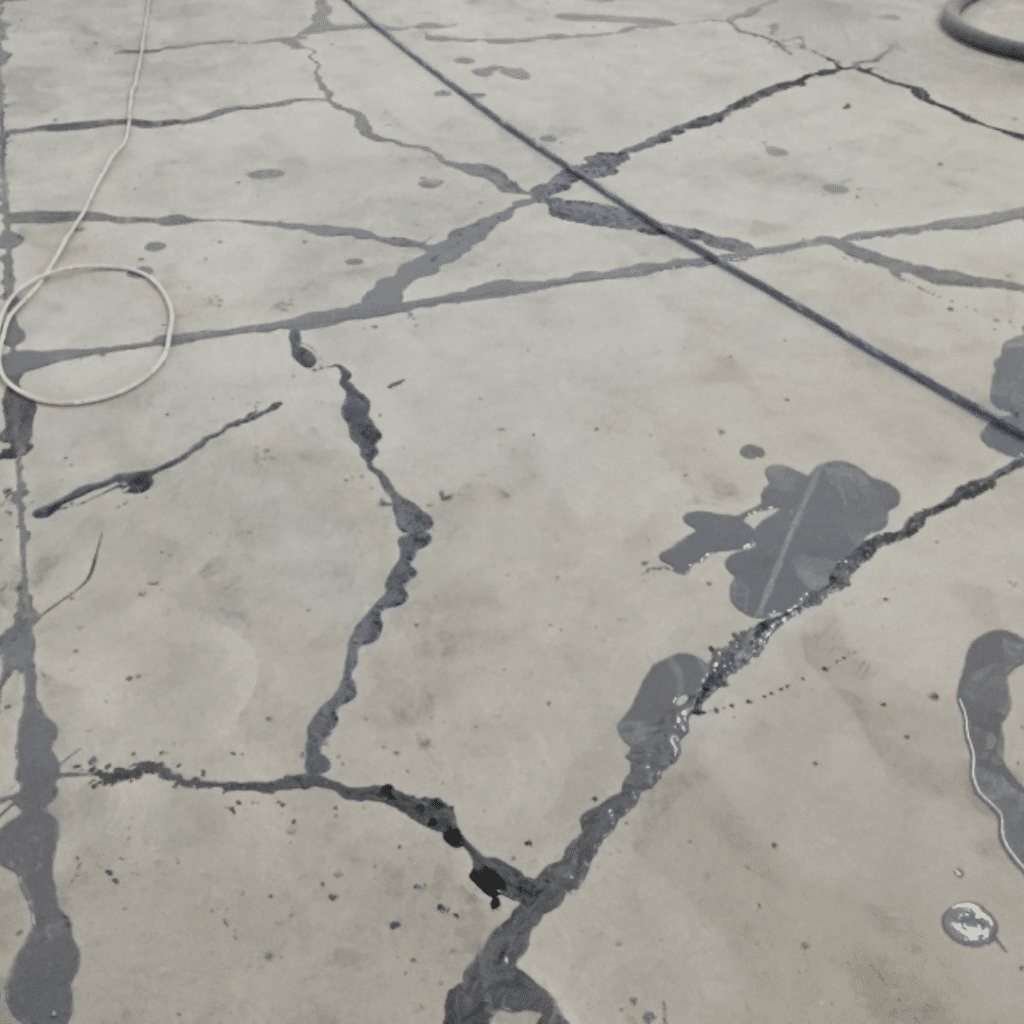 Image of a professional applying quick patch concrete crack repair material to a damaged concrete surface to fill and seal the crack.