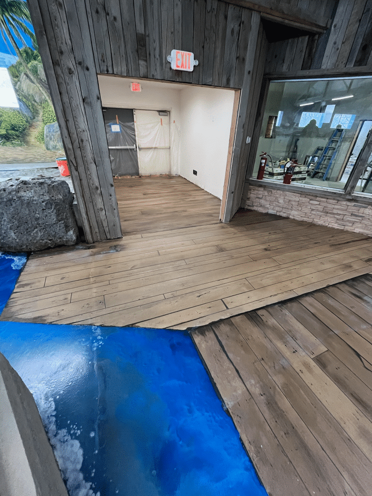 Image of a retail floor with a Rustic Wood Stamped Concrete flooring system. The flooring features a stamped pattern resembling rustic wood with natural variations in color and texture, providing a durable and attractive surface for high-traffic areas.